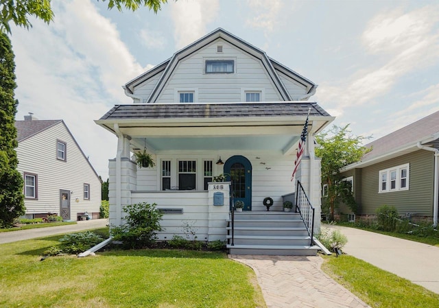 168 14th St, Fond Du Lac, WI 54935 - colonial inspired home with covered porch, a gambrel roof, a front yard, and a shingled roof