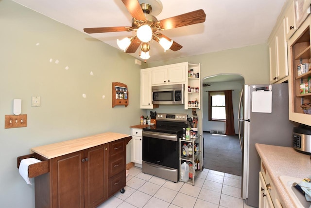 10526 W Congress St, Wauwatosa, WI 53225 - kitchen with stainless steel appliances, open shelves, arched walkways, light tile patterned floors, and white cabinets