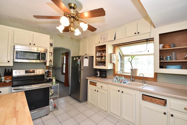 10526 W Congress St, Wauwatosa, WI 53225 - kitchen featuring appliances with stainless steel finishes, light tile patterned flooring, ceiling fan, arched walkways, and white cabinets