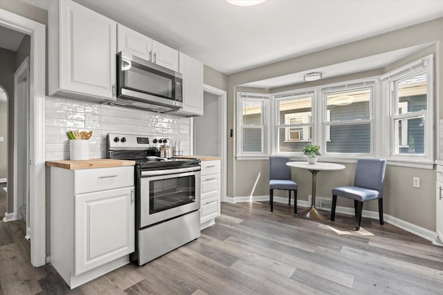 4455 N 58th St, Milwaukee, WI 53218 - kitchen with appliances with stainless steel finishes, wooden counters, light wood-style floors, decorative backsplash, and white cabinetry