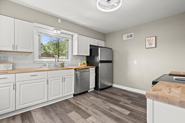4455 N 58th St, Milwaukee, WI 53218 - kitchen with appliances with stainless steel finishes, butcher block counters, dark wood-type flooring, decorative backsplash, and white cabinetry