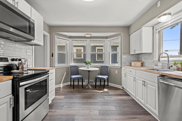 4455 N 58th St, Milwaukee, WI 53218 - kitchen featuring appliances with stainless steel finishes, backsplash, white cabinetry, and dark wood finished floors