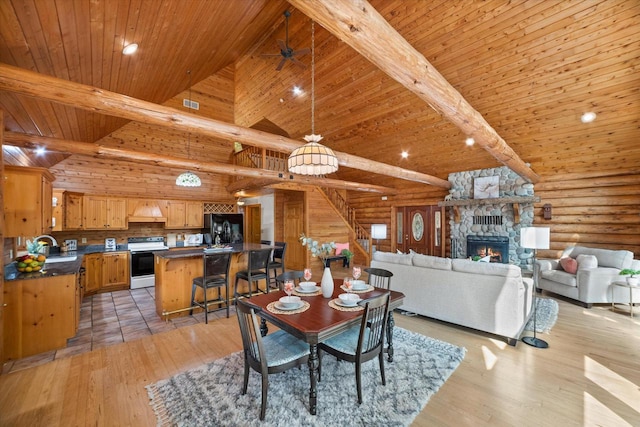5633 Contour Rd, Waterford, WI 53185 - dining area featuring rustic walls, stairway, a fireplace, light wood-style flooring, and a wooden ceiling with exposed beams