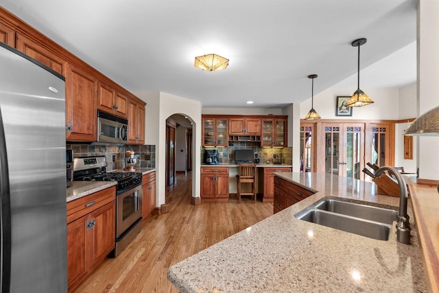 4570 Stoney Creek Rd, West Bend, WI 53095 - kitchen featuring appliances with stainless steel finishes, arched walkways, decorative backsplash, and brown cabinetry