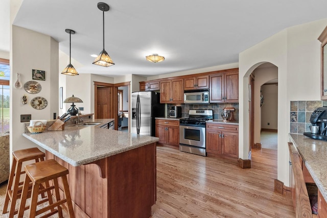 4570 Stoney Creek Rd, West Bend, WI 53095 - kitchen with stainless steel appliances, a breakfast bar, tasteful backsplash, and light wood finished floors
