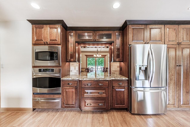 14240 Radiant Ct, Brookfield, WI 53005 - kitchen featuring appliances with stainless steel finishes, a warming drawer, light wood-type flooring, light stone countertops, and glass insert cabinets