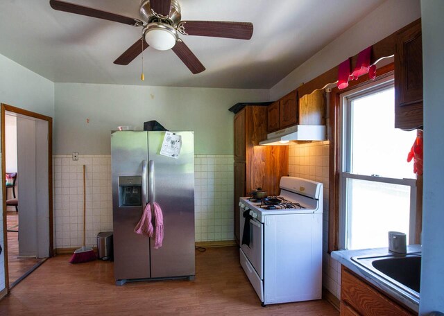 2110 54th St, Kenosha, WI 53140 - kitchen with stainless steel refrigerator with ice dispenser, white gas range oven, under cabinet range hood, tile walls, and light wood-style flooring