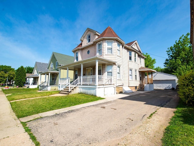2110 54th St, Kenosha, WI 53140 - view of front of house featuring covered porch, a garage, a front yard, and an outbuilding