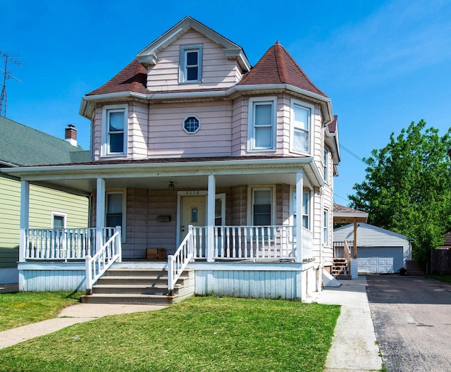 2110 54th St, Kenosha, WI 53140 - victorian home with covered porch, a detached garage, an outbuilding, and a front lawn