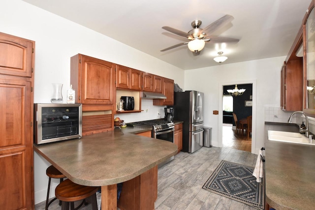 1032 Russet St, Racine, WI 53405 - kitchen with appliances with stainless steel finishes, under cabinet range hood, decorative backsplash, ceiling fan, and a breakfast bar