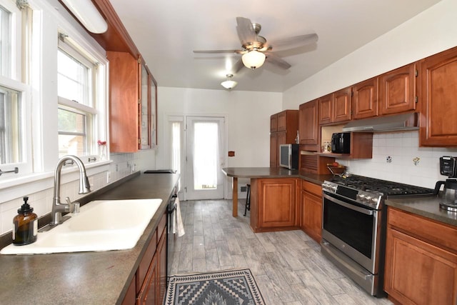 1032 Russet St, Racine, WI 53405 - kitchen with stainless steel gas stove, under cabinet range hood, dark countertops, and tasteful backsplash