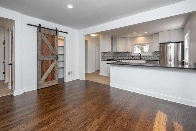 1120 N 124th St, Wauwatosa, WI 53226 - kitchen with freestanding refrigerator, a barn door, dark countertops, decorative backsplash, and dark wood finished floors