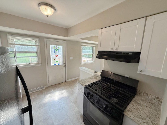 5082 N 108th St, Milwaukee, WI 53225 - kitchen with black gas stove, under cabinet range hood, white cabinetry, and light stone countertops