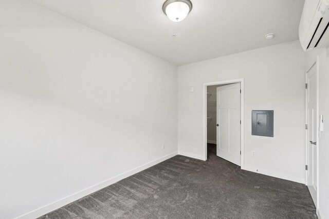 1601 N Windsor Ave Unit 106, Cottage Grove, WI 53527 - unfurnished bedroom featuring electric panel, an AC wall unit, dark carpet, a walk in closet, and a closet