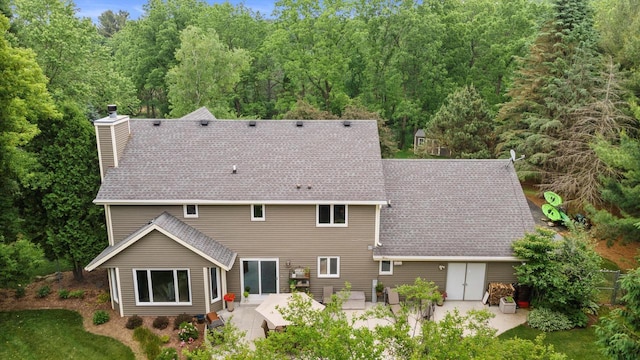 N80W32229 Northbrook Ct, Hartland, WI 53029 - back of property featuring a patio area, a chimney, roof with shingles, and a forest view