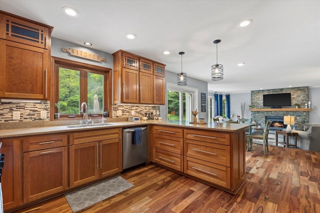 N80W32229 Northbrook Ct, Hartland, WI 53029 - kitchen with stainless steel dishwasher, a peninsula, a stone fireplace, backsplash, and dark wood-type flooring
