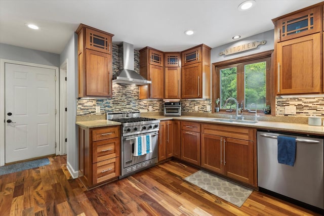 N80W32229 Northbrook Ct, Hartland, WI 53029 - kitchen featuring wall chimney range hood, appliances with stainless steel finishes, brown cabinetry, dark wood-style flooring, and recessed lighting