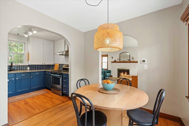 4705 Gordon Ave, Monona, WI 53716 - dining space with arched walkways, light wood-type flooring, and a stone fireplace