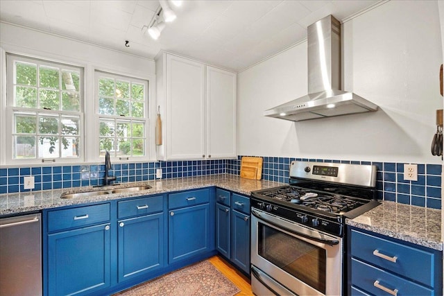 4705 Gordon Ave, Monona, WI 53716 - kitchen featuring appliances with stainless steel finishes, wall chimney range hood, blue cabinets, and light stone countertops