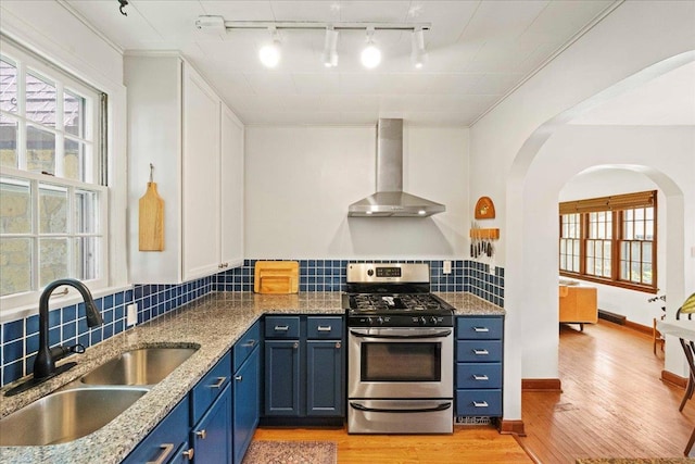 4705 Gordon Ave, Monona, WI 53716 - kitchen with gas range, wall chimney range hood, rail lighting, blue cabinetry, and light wood-style flooring