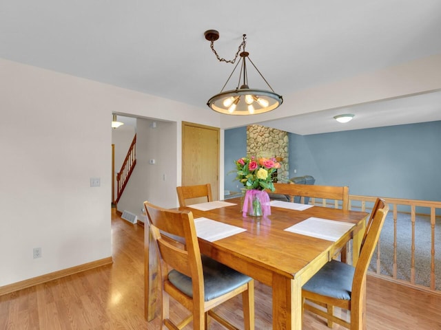 26317 Dukleth Dr, Waterford, WI 53185 - dining area with stairs, light wood finished floors, and a chandelier