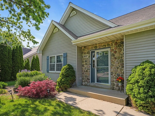 26317 Dukleth Dr, Waterford, WI 53185 - property entrance featuring stone siding, a shingled roof, and a porch