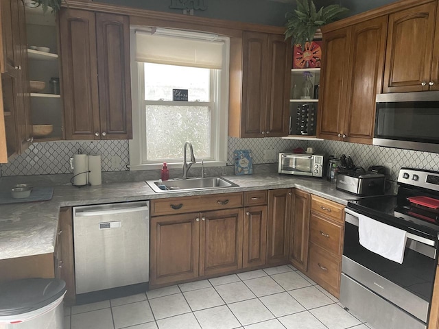 840 Lincoln Blvd, Manitowoc, WI 54220 - kitchen with stainless steel appliances, backsplash, light tile patterned flooring, and brown cabinets