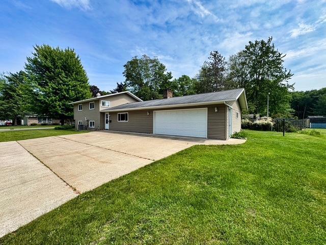 2709 Richard St, Marinette, WI 54143 - tri-level home with a front lawn, a chimney, and a garage