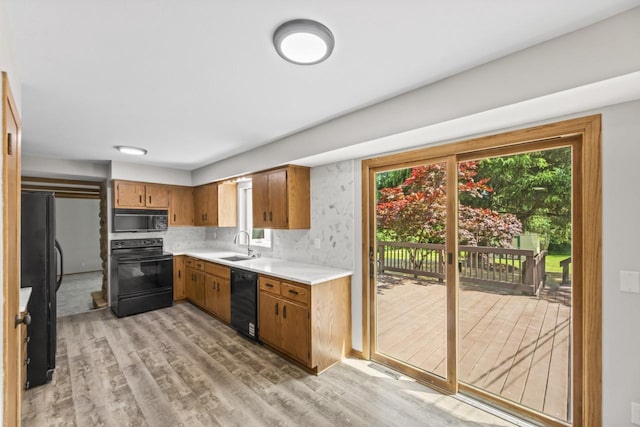 6101 W Edgerton Ave, Greendale, WI 53129 - kitchen with black appliances, light countertops, brown cabinetry, and light wood finished floors