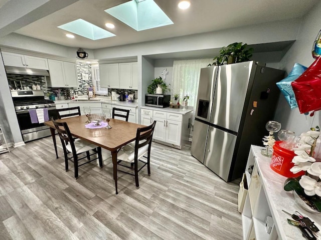 5510 W Luebbe Ln, Milwaukee, WI 53223 - kitchen featuring appliances with stainless steel finishes, under cabinet range hood, a skylight, light countertops, and white cabinets