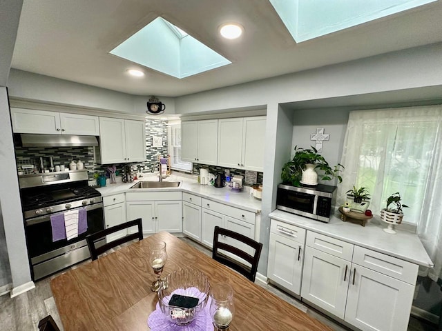 5510 W Luebbe Ln, Milwaukee, WI 53223 - kitchen featuring appliances with stainless steel finishes, a skylight, decorative backsplash, white cabinetry, and recessed lighting
