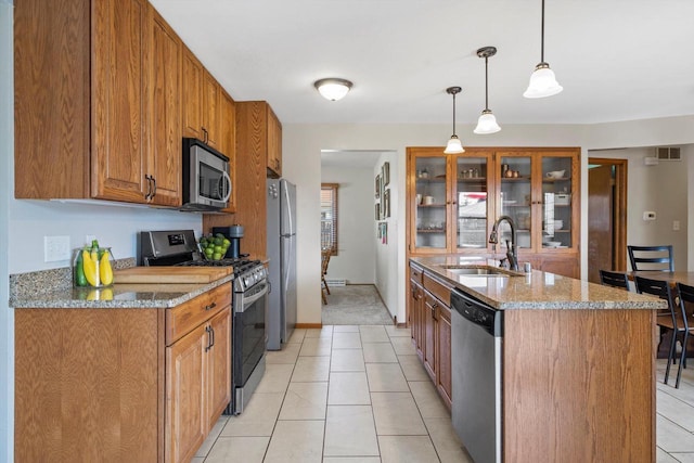 7939 32nd Ave, Kenosha, WI 53144 - kitchen with stainless steel appliances, brown cabinetry, light tile patterned flooring, and light stone counters