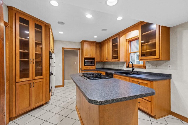 928 Emilie St, Green Bay, WI 54301 - kitchen featuring gas stovetop, dark countertops, brown cabinets, a center island, and glass insert cabinets