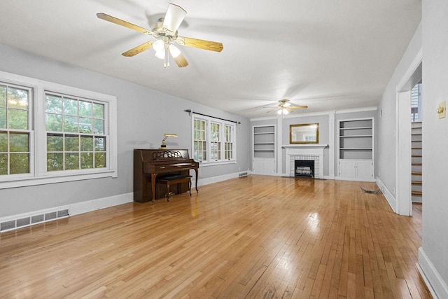 928 Emilie St, Green Bay, WI 54301 - living area with a ceiling fan, built in features, light wood finished floors, and a brick fireplace