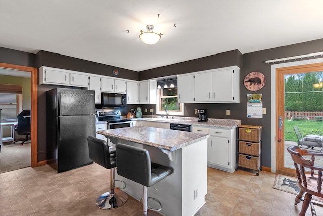 3987 Elaines Way, Slinger, WI 53086 - kitchen featuring black appliances, light countertops, white cabinets, a center island, and a kitchen breakfast bar