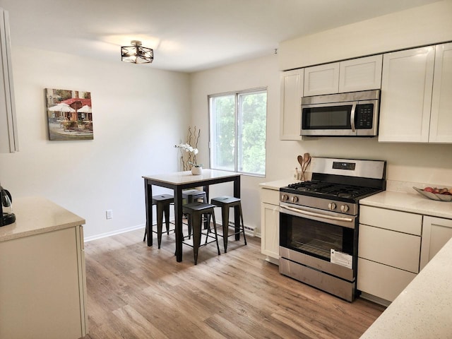 1239 Erick St, Fort Atkinson, WI 53538 - kitchen with appliances with stainless steel finishes, light wood finished floors, and white cabinetry