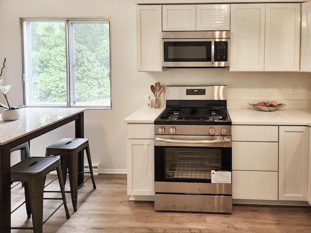 1239 Erick St, Fort Atkinson, WI 53538 - kitchen featuring stainless steel appliances, light wood-type flooring, light countertops, white cabinetry, and baseboard heating