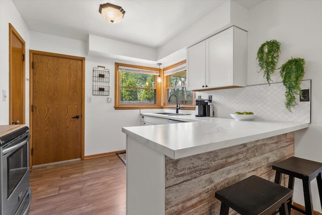 10822 W Derby Ave, Wauwatosa, WI 53225 - kitchen with stainless steel electric stove, a breakfast bar, a peninsula, light countertops, and white cabinets