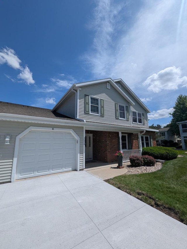 2524 Village Ln Unit B, Oshkosh, WI 54904 - traditional-style home with concrete driveway, covered porch, an attached garage, brick siding, and a front yard