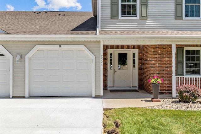 2524 Village Ln Unit B, Oshkosh, WI 54904 - view of exterior entry with roof with shingles, brick siding, concrete driveway, and covered porch