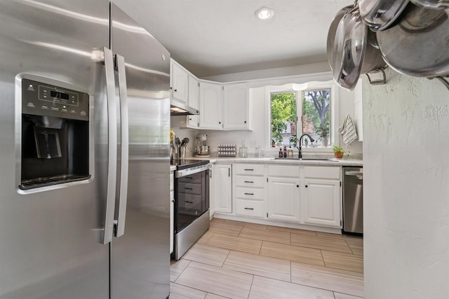266 E 10th St, Fond Du Lac, WI 54935 - kitchen with stainless steel appliances, under cabinet range hood, white cabinetry, and light countertops