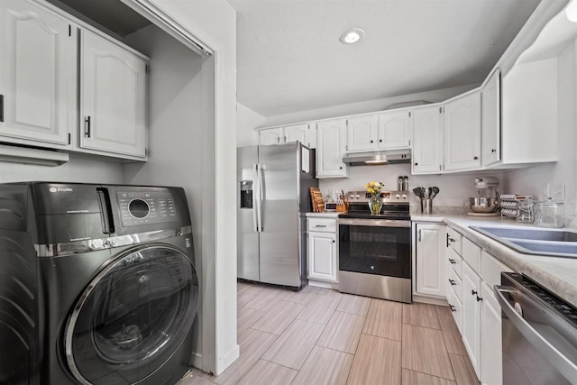 266 E 10th St, Fond Du Lac, WI 54935 - kitchen with washer / clothes dryer, appliances with stainless steel finishes, under cabinet range hood, white cabinetry, and light countertops
