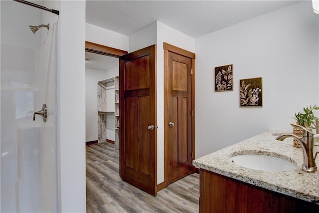 1724 Dorret Rd, Eau Claire, WI 54703 - bathroom featuring wood finished floors, double vanity, a shower, and a textured ceiling