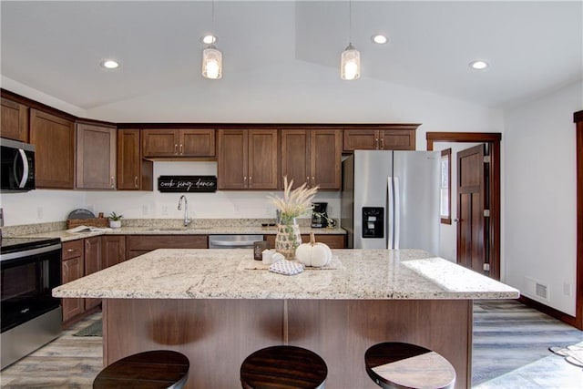 1724 Dorret Rd, Eau Claire, WI 54703 - kitchen with appliances with stainless steel finishes, vaulted ceiling, wood finished floors, a breakfast bar, and recessed lighting