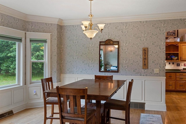 704 Sandy Pines Ct, Redgranite, WI 54970 - dining space featuring light wood-style floors, healthy amount of natural light, a decorative wall, a wainscoted wall, and crown molding