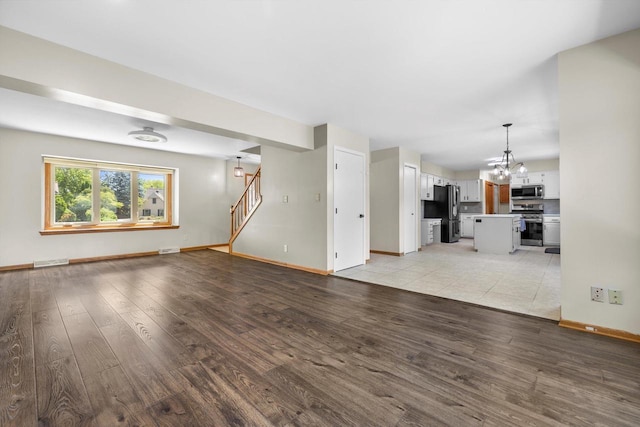 8206 41st Ave, Kenosha, WI 53142 - unfurnished living room with light wood-style floors, stairway, and a chandelier