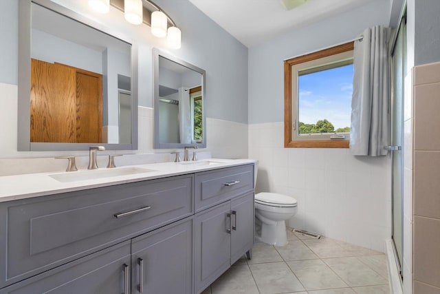 8206 41st Ave, Kenosha, WI 53142 - bathroom with tile walls, a shower stall, double vanity, tile patterned flooring, and a wainscoted wall