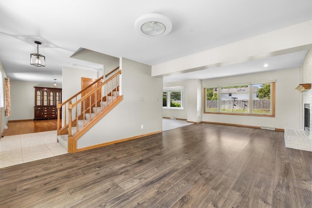 8206 41st Ave, Kenosha, WI 53142 - unfurnished living room with stairway, wood finished floors, and a brick fireplace
