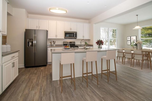 415 Kensington Ct Unit Lt128Adams, Williams Bay, WI 53191 - kitchen with appliances with stainless steel finishes, dark wood-style floors, white cabinetry, a center island with sink, and a kitchen bar