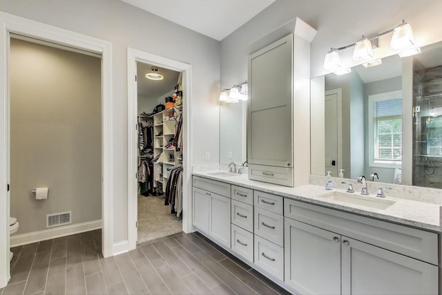 9335 223rd Ave, Salem, WI 53168 - bathroom featuring double vanity, a walk in closet, and wood finished floors